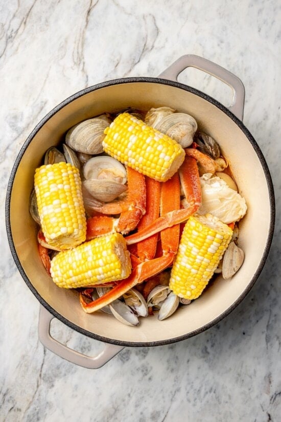 Overhead view of corn added to pot of seafood