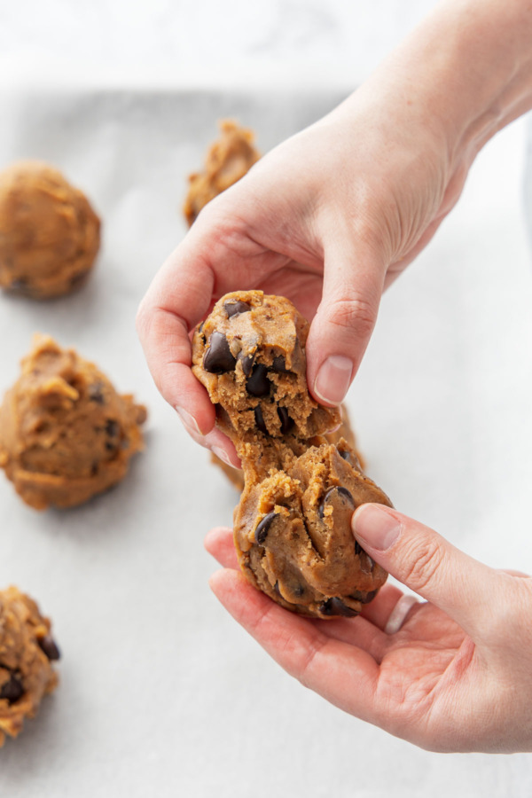 Breaking a dough ball into two smaller balls.