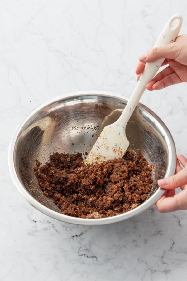 Mixing sugar and brown sugar into brown butter in a mixing bowl.